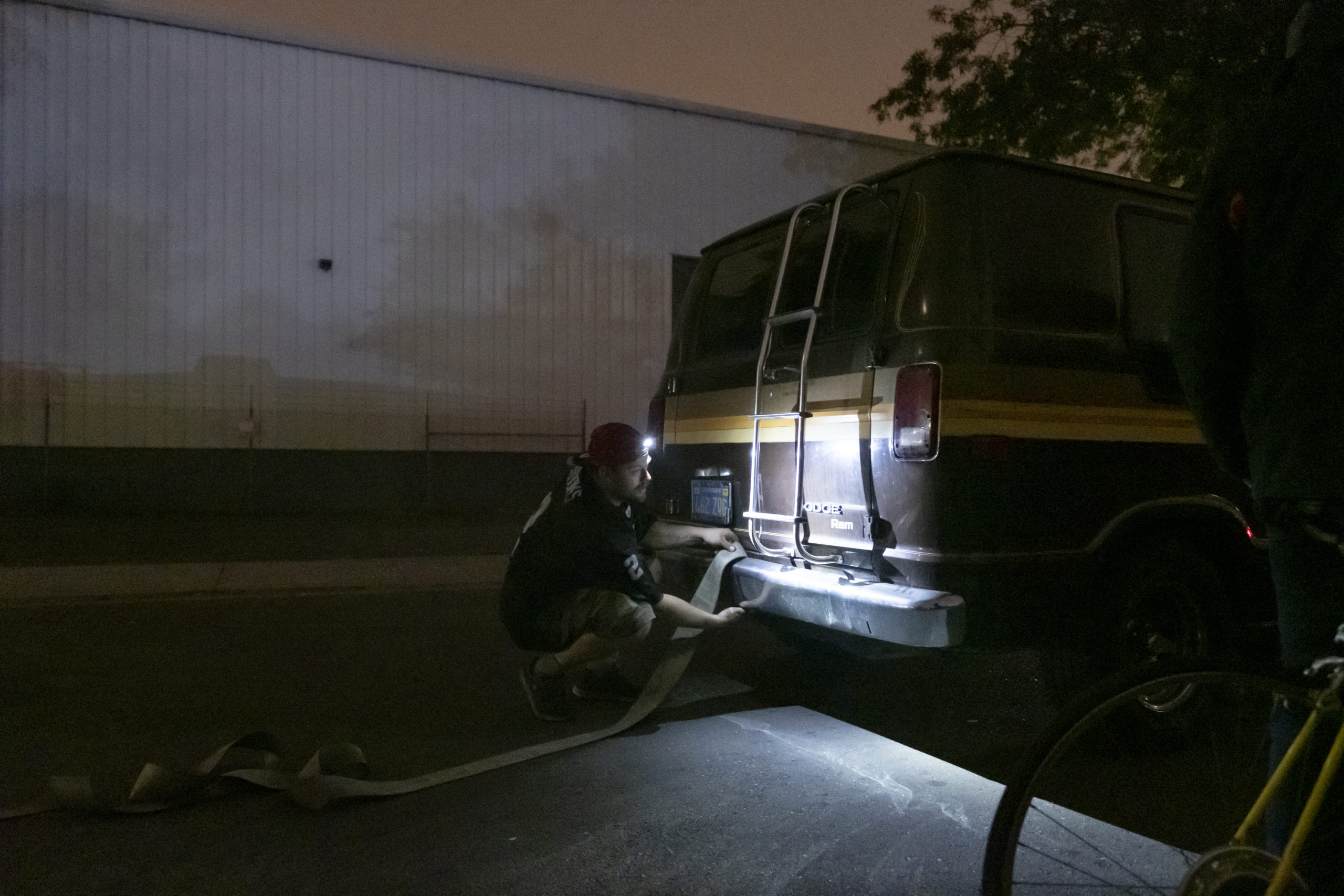 Chris Castle ties a tow strap to the bumper of Amber Whitson’s Dodge van on a Sunday night to help his friend Ryan Maddry, whose vehicle was red-tagged with a 72-hour notice, giving him a warning to move or be towed. But the “Ole Gal” is in disrepair and barely makes it around the corner. As a last resort, vehicle residents band together and use human force, pushing their vehicles by hand or pulling them with ropes. It is challenging to find new parking places and get resituated every three days. Chris Castle ties a tow strap to the bumper of Amber Whitson’s Dodge van on a Sunday night to help his friend Ryan Maddry, whose vehicle was red-tagged with a 72-hour notice, giving him a warning to move or be towed. But the “Ole Gal” is in disrepair and barely makes it around the corner. As a last resort, vehicle residents band together and use human force, pushing their vehicles by hand or pulling them with ropes. It is challenging to find new parking places and get resituated every three days.