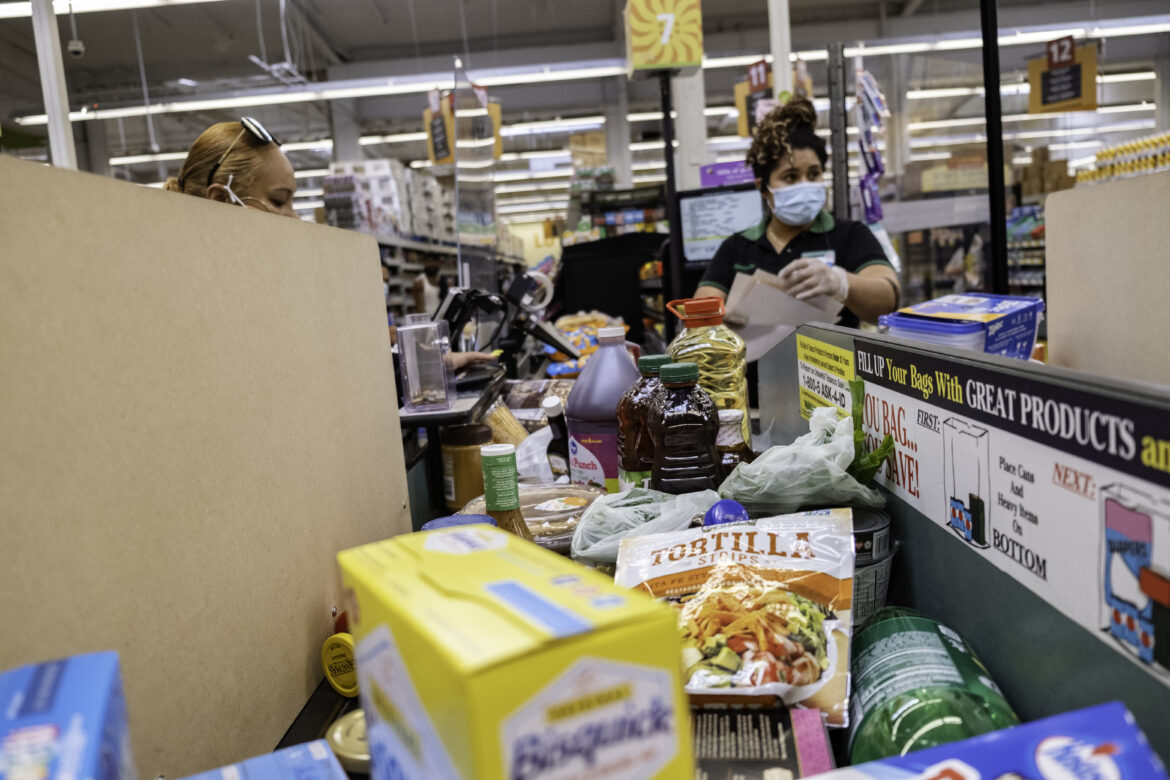 After scanning a shopping cart full of food, Tolbert hands the cashier her monthly vouchers to pay for her groceries at Foods Co. She saves her weekly food vouchers until the end of the month to stock up during one trip. The vouchers do not always cover the total, but Tolbert is able to use her CalFresh and WIC benefits to cover the rest.