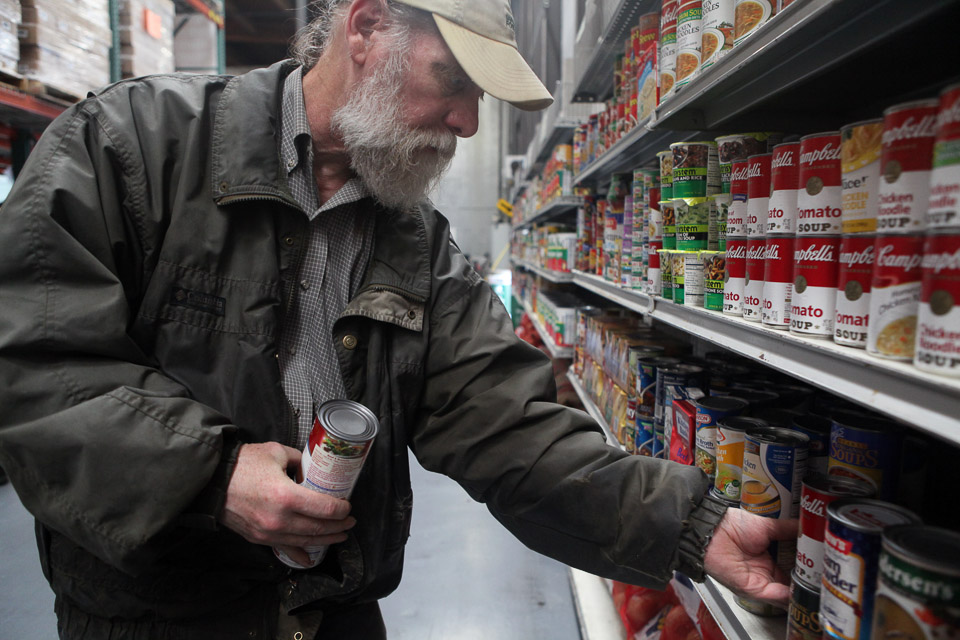 File photo: San Francisco Food Bank volunteer Jim Caddick stocks shelves with soup in 2012.
