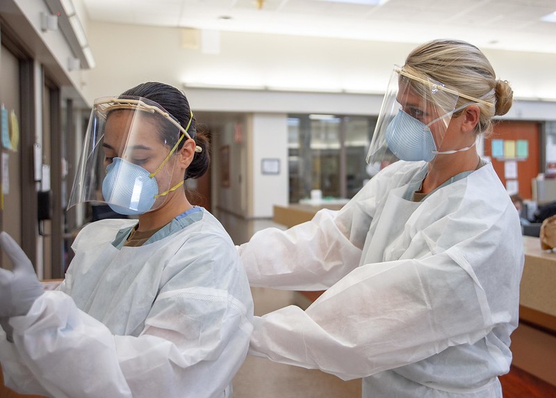 Ensign Kaitlyn Leibing, right, a staff nurse assigned to one of Naval Medical Center San Diego’s internal medicine wards, helps Hospitalman Angela Mello don personal protective equipment before entering a COVID-19-positive, non-critical patient’s room on Aug. 4, 2020.