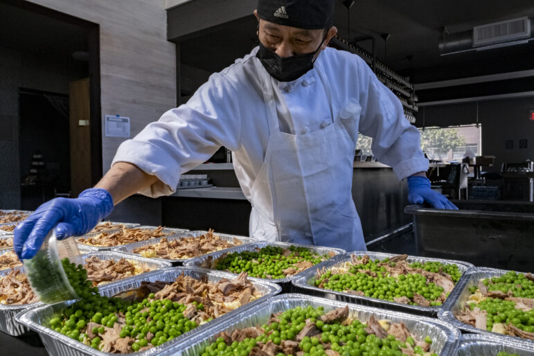 Line cook Jose Mcha prepares turkey and pasta dinners for charity distribution.