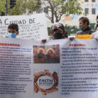 Protesters hold a sign listing demands, in English and Spanish, regarding San Francisco's rent assistance program.