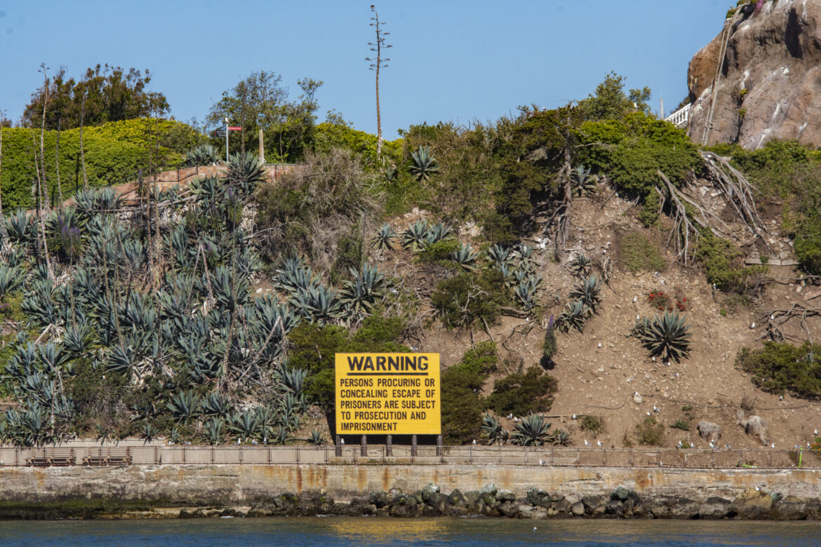 A yellow warning sign from Alcatraz‘s prison era on the agave trail cautions that visitors “concealing escape of prisoners are subject to prosecution and imprisonment.”