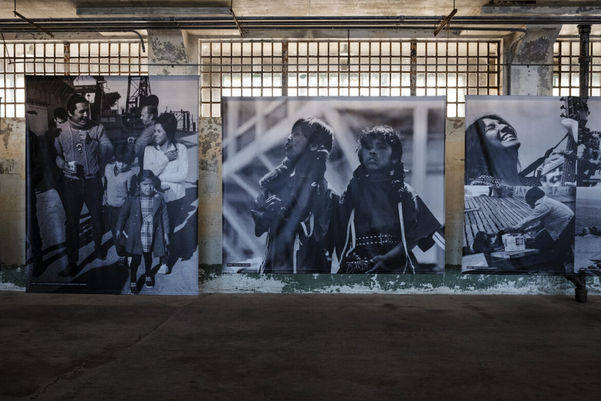 Large photos on canvases depict young families and children on Alcatraz during the occupation.