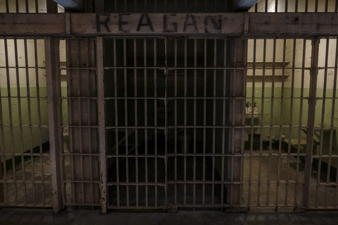 A cell at Alcatraz with "Reagan" painted over the cell door.