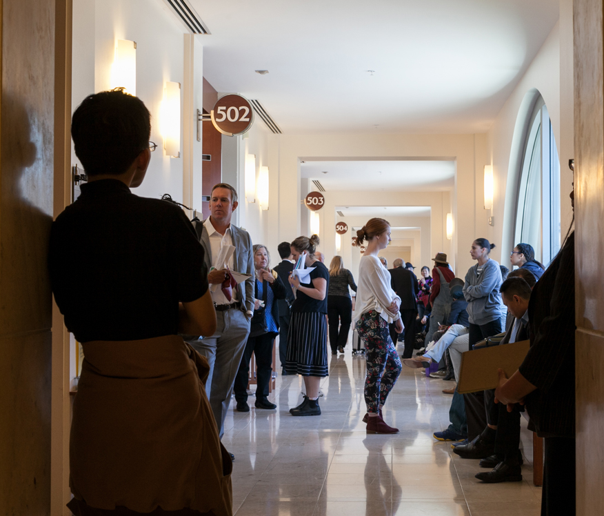 More than a dozen people stand in a hallway leading to courtrooms in San Francisco.