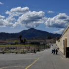 Several men gather just outside a building at San Quentin prison, with Mt. Tamalpais framed by dramatic clouds in the background. Four prisoners a tSan Quentin have tested positive for COVID-19 and their housing unit is under quarantine.