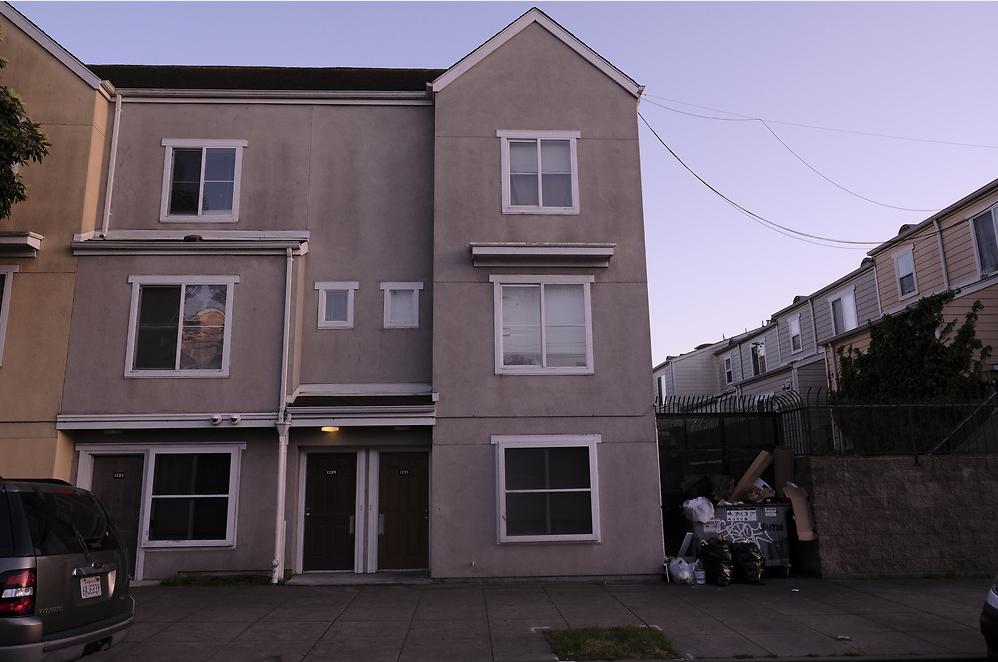 A street view of a complex of three-story apartment buildings.