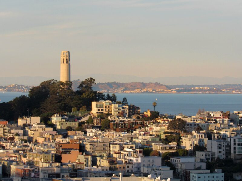Coit Tower and the San Francisco Bay are seen behind apartment buildings in San Francisco's North Beach neighborhood.