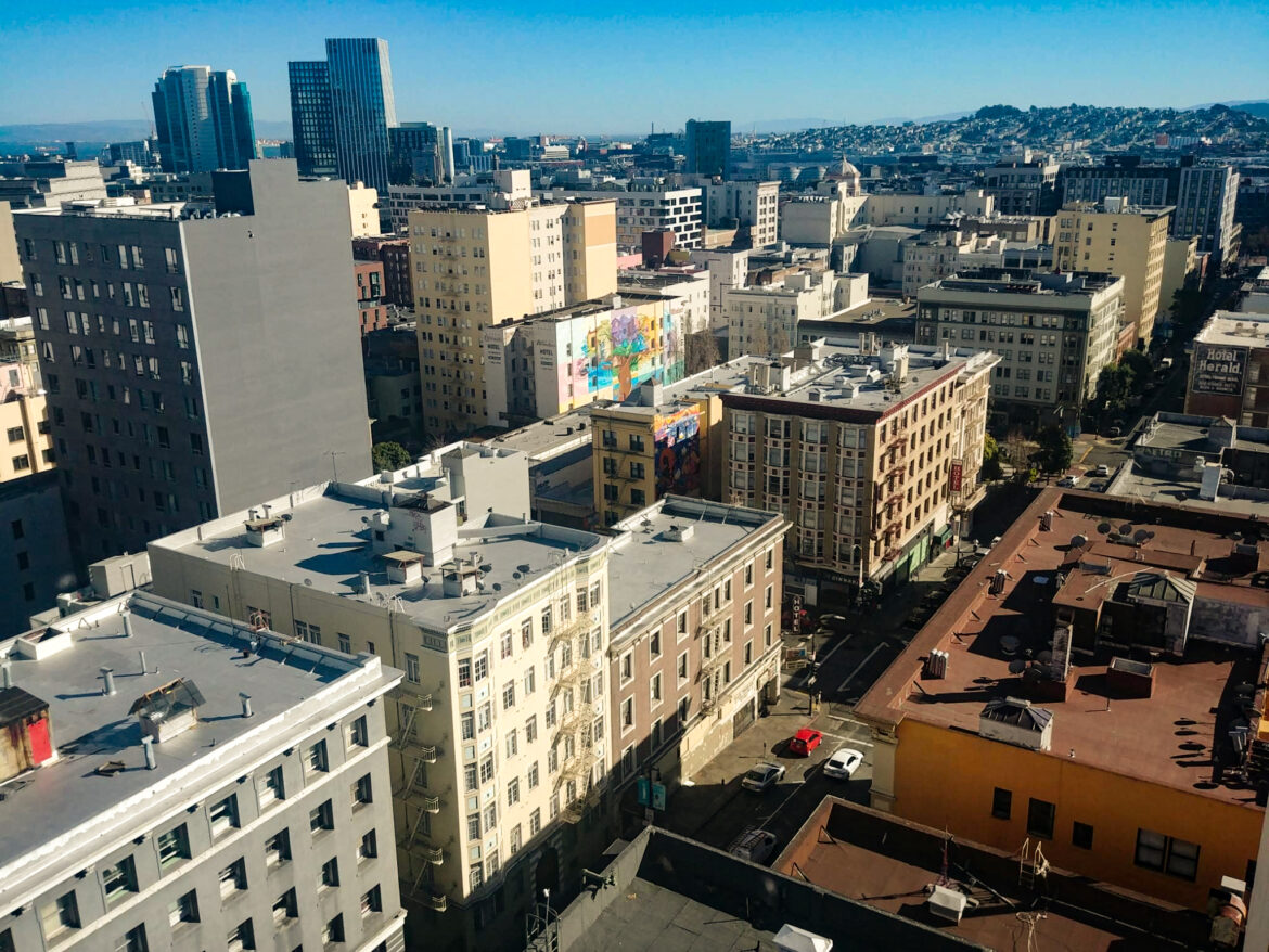 A birds-eye view of several multi-story apartment buildings, with downtown San Francisco in the background.
