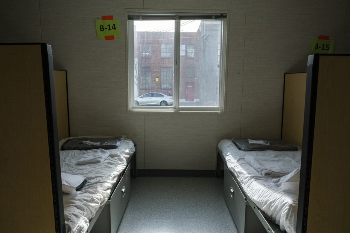 Two beds sit on either side of a window at a navigation center for transgender homeless people.