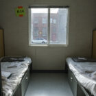 Two beds sit on either side of a window at a navigation center for transgender homeless people.