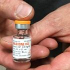hands holding a vial of naloxone