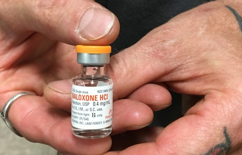 hands holding a vial of naloxone
