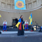 Singer at benefit concert with Ukrainian flags.