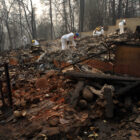 Workers in white suits sift through burned debris after the Camp Fire, the largest in California history.