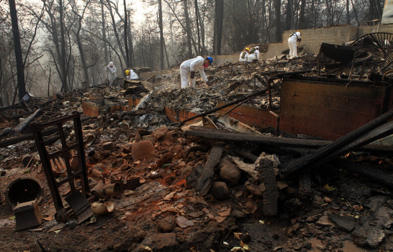 Workers in white suits sift through burned debris after the Camp Fire, the largest in California history.