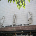 The entrance to Los Angeles Superior Court's Stanley Mosk Courthouse is shown, with three robed stone figures above the doorway.