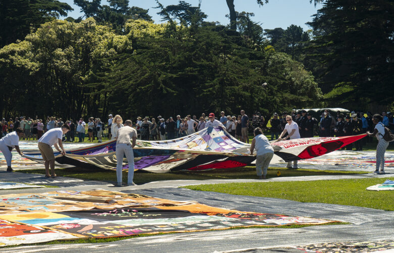 Volunteers spread open a panel of the AIDS Memorial Quilt during an opening ceremony on Saturday, June 11, 2022, at Robin Williams Meadow in Golden Gate Park. This was the largest display of the quilt since it was shown in Washington, D.C., in 2012.