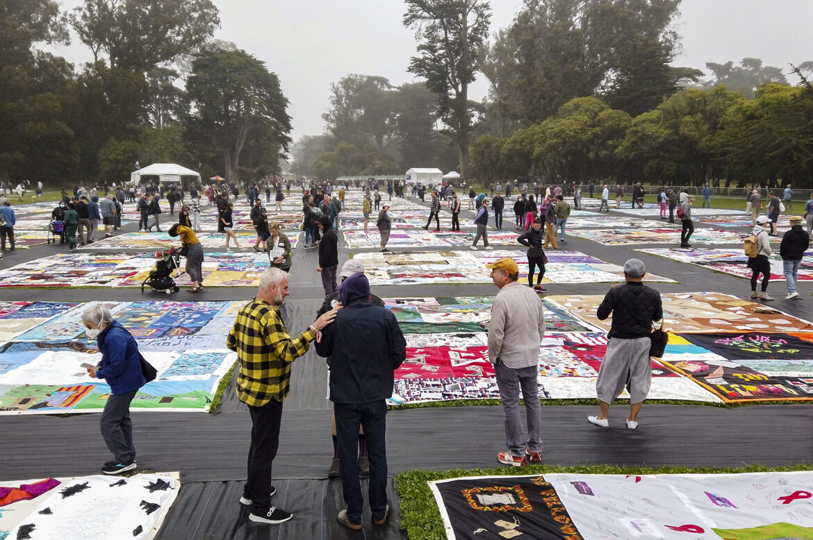 Visitors walk through Robin Williams Meadow, gazing down at the AIDS Memorial Quilt panels where colorful fabric blocks have been sewn together honoring the lives of people who have died from AIDS. Visitors share stories, hugs and tears as they walk through the art piece.