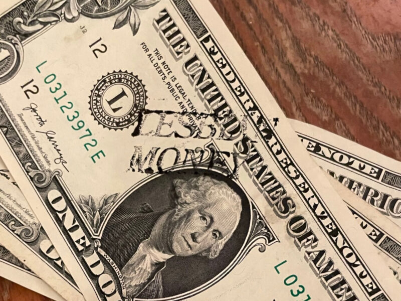 A one dollar bill with the words lesbian money stamped on it next to George Washington's portrait.