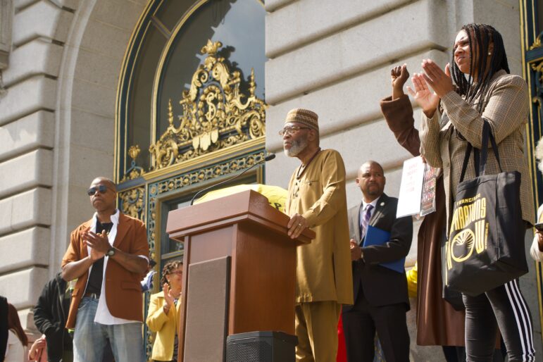 The Rev. Amos Brown speaks at a lectern in front of City Hall.