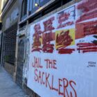 Graffiti covers a poster with the words "Jail the Sacklers"