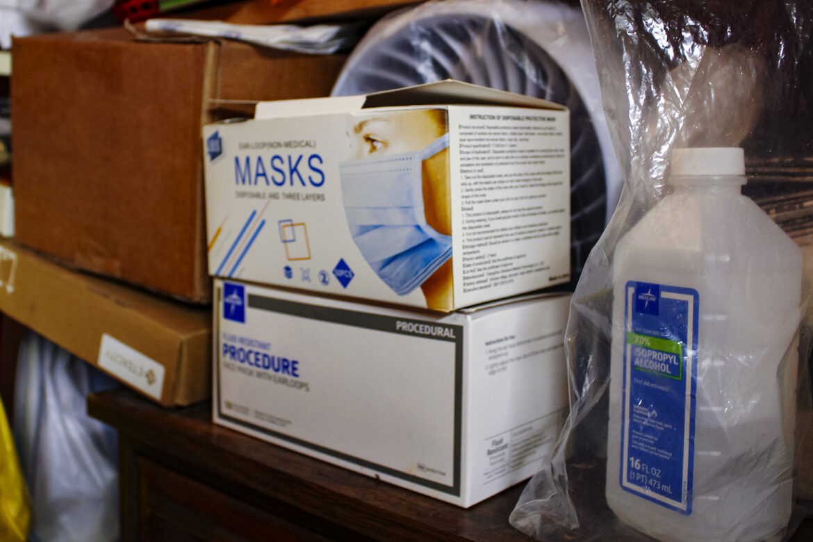 Two boxes of surgical masks and a bottle of rubbing alcohol on a counter.