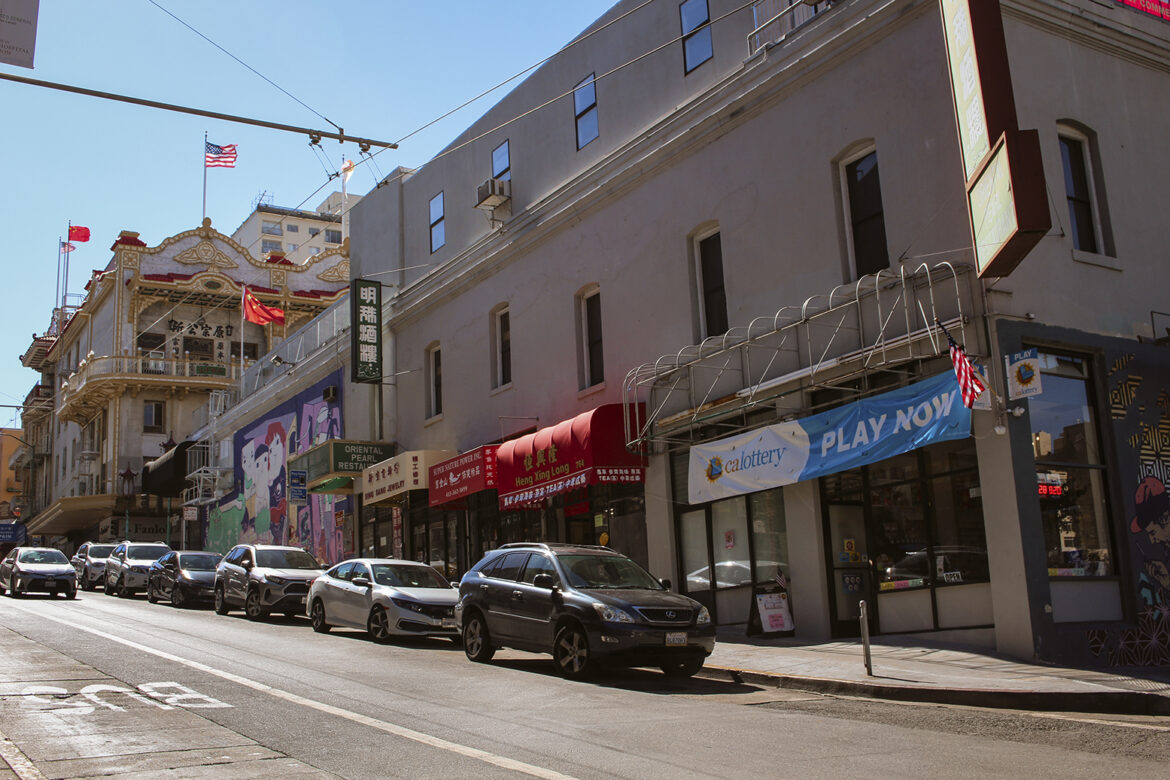 Cars are parked along an inclined street in San Francisco's Chinatown.