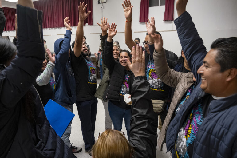 A circle of attendees cheer at a community event.