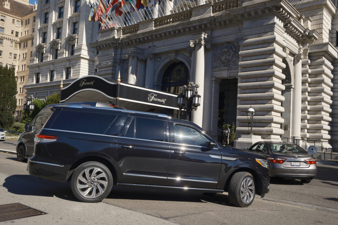 A large black SUV turns into the driveway at the main visitor entrance of the Fairmont Hotel.