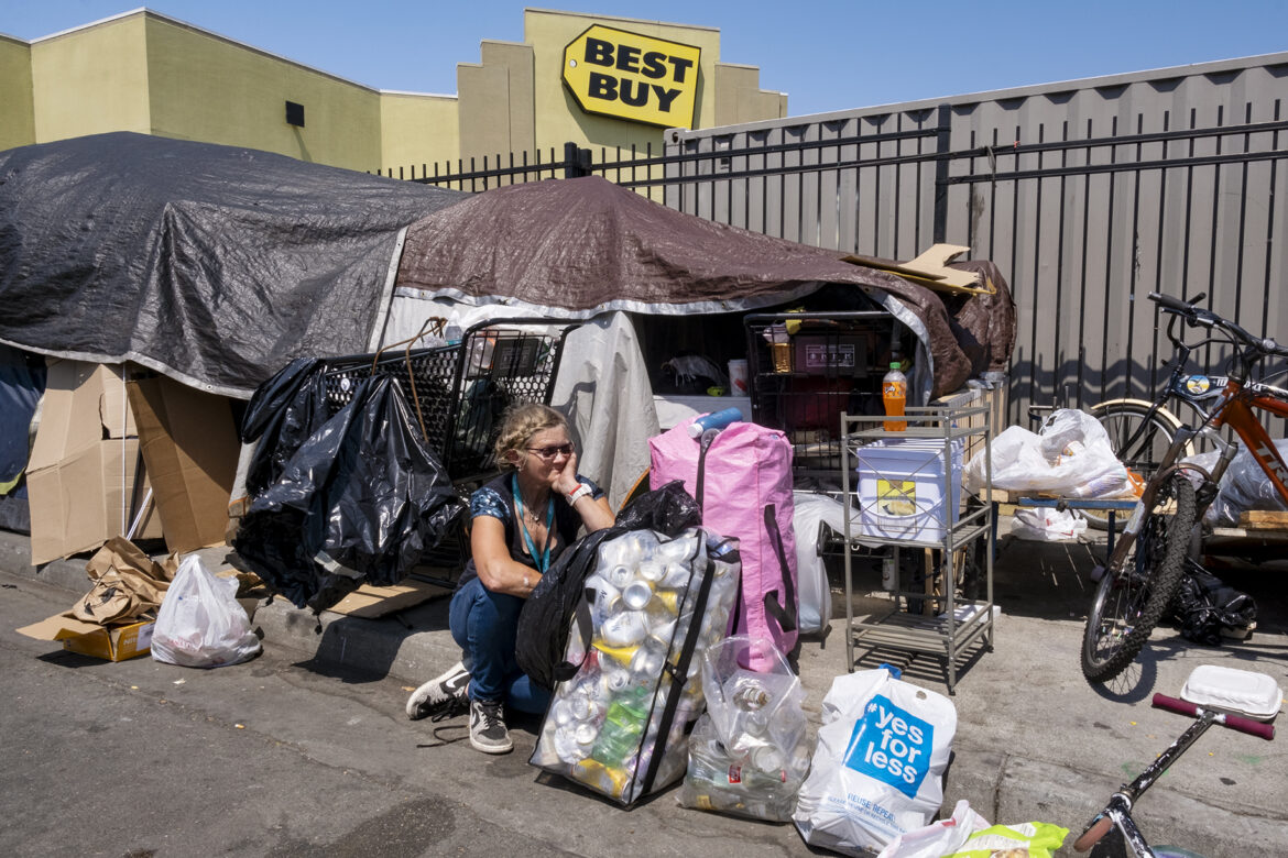A woman sits among her possessions in a homeless encampment in San Francisco, near the Best Buy on the edge of the city’s Mission District.