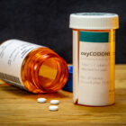 Two oxycodone medicine bottles, with one on its side with pills spilling out