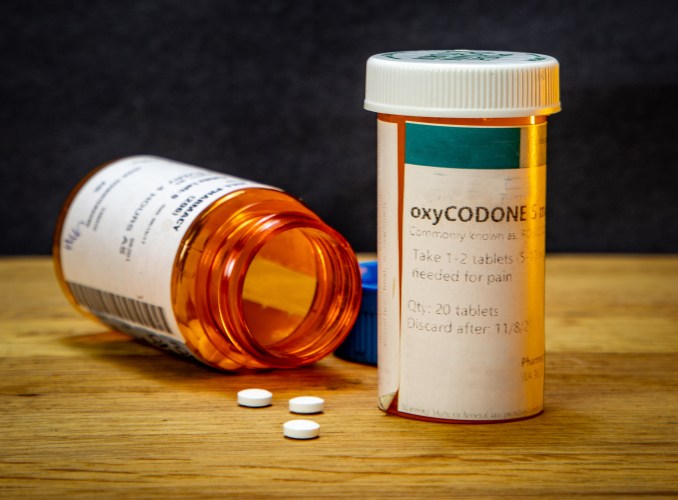 Two oxycodone medicine bottles, with one on its side with pills spilling out