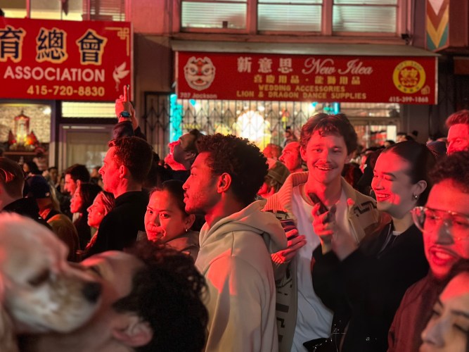 A crowd of people watch a music show, their faces lit, at Mayor Daniel Lurie’s inaugural party in Chinatown.