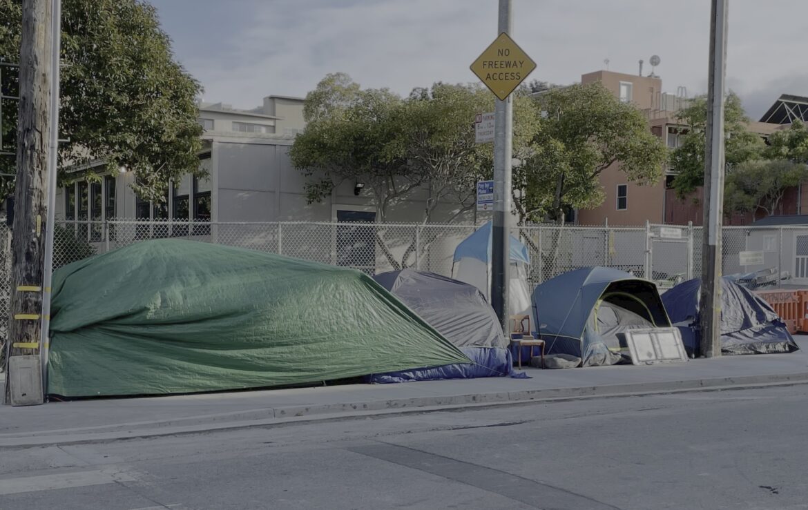 Tents line a sidewalk along a quiet city street.