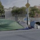 Tents line a sidewalk along a quiet city street.