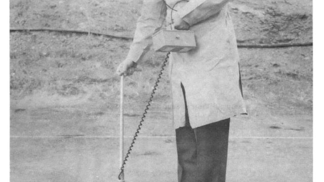 Scientists at the Naval Radiological Defense Laboratory tested prototype devices in the 1950s to detect radiation levels in the field. Challenges in measuring pollutants at the site continue to the present day despite technological advancements. Source: Naval Radiological Defense Laboratory via Bureau of Ships Journal, 1959. black-and-white image of a man outdoors holding a geiger counter measuring the ground