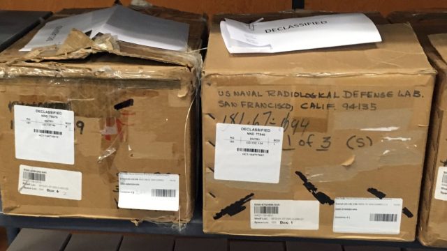 Much of the lab’s remaining paper record is crumbling and faded, stored in cardboard boxes at the National Archives and Records Administration repository in San Bruno, Calif. Some documents were declassified at the request of journalists on this project.
Photo by Chris Roberts / San Francisco Public Press A row of cardboard boxes on a shelf labeled U.S. Naval Radiological Lab and with stickers saying "declassified"