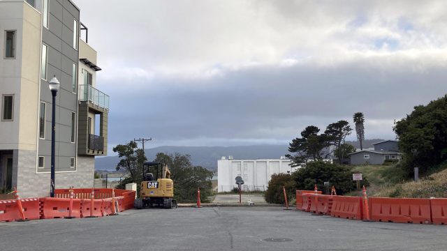 Owners of new condominiums sued the developer and the Navy, alleging they were misled about the health threat from the shipyard. The radiation lab’s white, nearly windowless former headquarters remains a looming presence on residential streets. A street lined with new mid-rise homes under construction and a white, windowless building in the distance