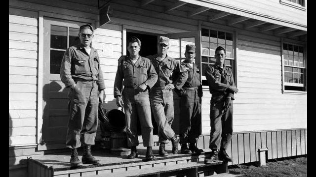 Eldridge Jones, center, and fellow soldiers received radiation exposure in Nevada nuclear weapons tests, and later in Bay Area land decontamination experiments. Source: 50th Chemical Platoon Blog. five men in uniform stand casually on a wooden porch in a black-and-white photo