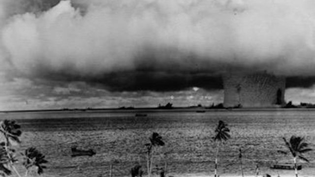 The Naval Radiological Defense Laboratory got its start after the U.S. began testing atomic bombs in the Pacific. When ships irradiated in Operation Crossroads at Bikini Atoll in 1946 were towed to San Francisco, lab scientists monitored radiation exposure of workers tasked with decontaminating them. Source: National Archives and Records Administration. A black-and-white photo of a mushroom cloud growing over ships at sea, with a tropical island shore in the foreground